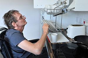 accessible housing - a man in a wheelchair uses accessible kitchen